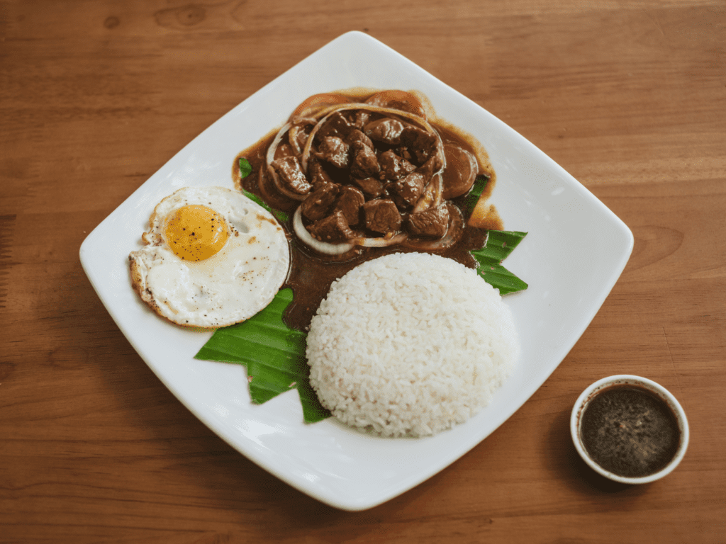 Cambodian Lok Lak, a stir-fried beef dish served with rice, a fried egg, and black pepper dipping sauce. A top food experience in best places to visit in Cambodia.