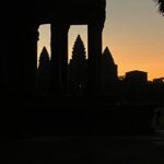 Angkor Wat temple framed by ancient stone pillars at sunrise, creating a stunning contrast between light and shadow in Cambodia’s most famous landmark.