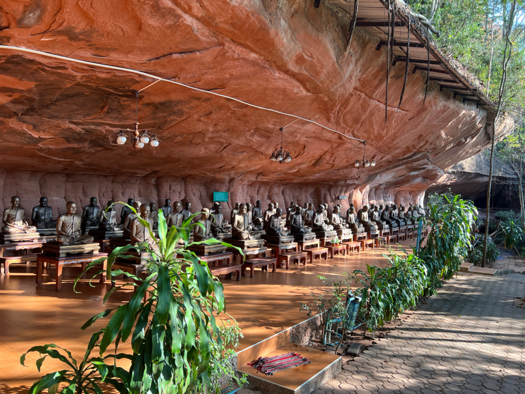 Hidden Thailand: A row of bronze monk statues in a cave temple at Wat Phu Tok, Unusual places in Thailand: Meditation statues of Buddhist monks in a hidden cave, Hidden gems in Thailand: A peaceful cave shrine with lifelike monk statues, Best secret spots in Thailand: A sacred meditation site with bronze monk figures, Off-the-beaten-path Thailand: A hidden Buddhist retreat with ancient statues in Bueng Kan