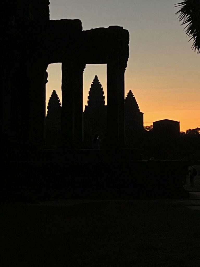 Angkor Wat temple framed by ancient stone pillars at sunrise, creating a stunning contrast between light and shadow in Cambodia’s most famous landmark.