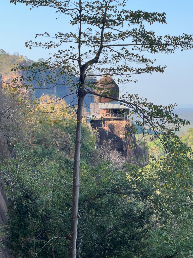 Hidden Thailand: A hidden wooden meditation hut on the cliffs of Wat Phu Tok, Unusual places in Thailand: Secluded monk retreat built into the rock face at Wat Phu Tok, Hidden gems in Thailand: A remote meditation hut nestled in the cliffs of Bueng Kan, Best secret spots in Thailand: A peaceful sanctuary high above the forest at Wat Phu Tok, Off-the-beaten-path Thailand: A spiritual escape overlooking the vast landscape of northeastern Thailand