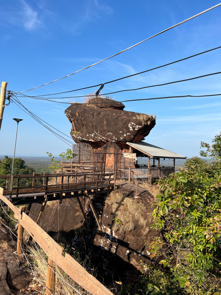 Hidden Thailand: A precarious wooden bridge leading to a meditation hut at Wat Phu Tok, Unusual places in Thailand: A temple perched on a rock with a breathtaking sky view, Hidden gems in Thailand: Wat Phu Tok’s cliffside meditation hut overlooking the valley, Best secret spots in Thailand: A sacred rock shrine built high above the ground, Off-the-beaten-path Thailand: A unique wooden walkway leading to a remote temple structure