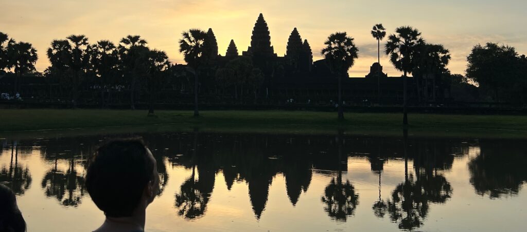 Sunrise over Angkor Wat in Siem Reap, Cambodia, with the temple’s silhouette reflected in the water, a stunning sight for travelers visiting this UNESCO World Heritage Site.